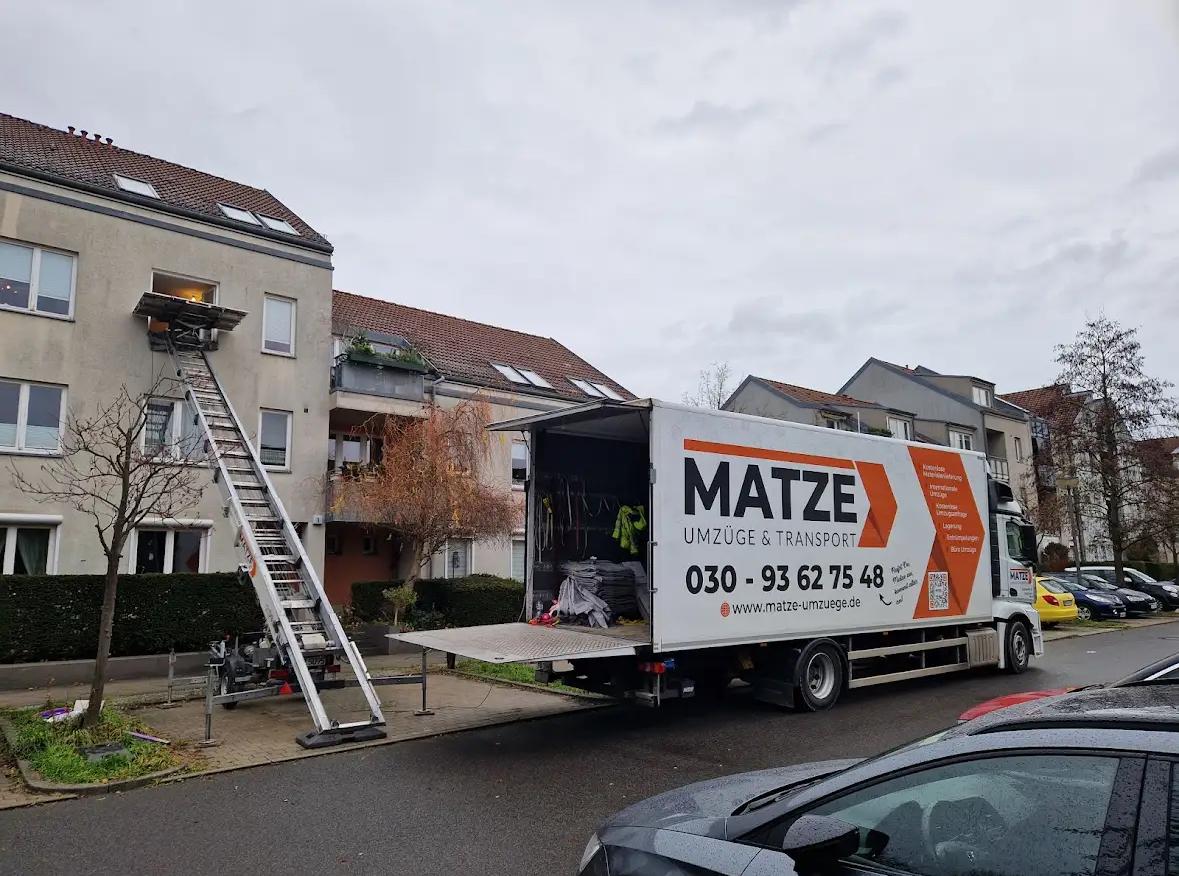 Ausgefahrener Möbellift an einem Mehrfamilienhaus, davor ein Umzugs-LKW von Matze Umzüge